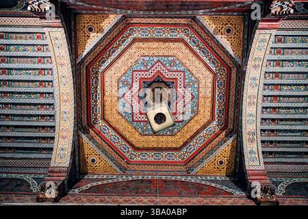 Tradizionale soffitto marocchino intagliato in legno caratterizzato da intricati motivi geometrici e colori vivaci, che mettono in risalto la ricca maestria artigianale Foto Stock