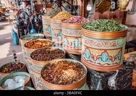Tradizionali contenitori metallici traboccanti di spezie colorate che creano una vivace esposizione in un vivace mercato di Marrakech Foto Stock