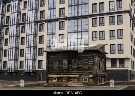 vecchia casa in legno sullo sfondo di un moderno edificio a più piani di nuova costruzione Foto Stock