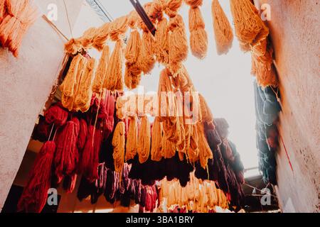 Filati di lana colorati appesi e asciugati in un tradizionale laboratorio di conceria marocchina a Marrakech Foto Stock
