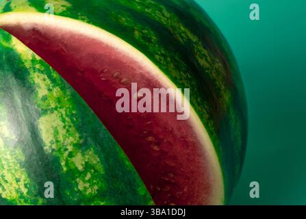 un primo piano mostra la polpa rossa vibrante e la crosta verde scuro di un anguria a fette Foto Stock