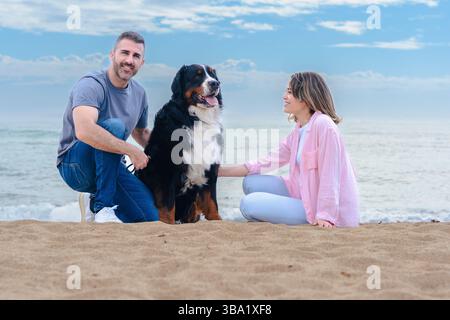 Ritratto caucasico di coppia con il cane in vacanza al mare sorridente alla macchina fotografica Foto Stock