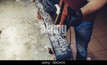Applicazione di cera calda a base di sci con ferro. Applicazione di cera di sci di fondo sci. Base di sci tuning. Sci wax ferro e barre di cera. Il servizio sci e riparazione. repairman in Foto Stock