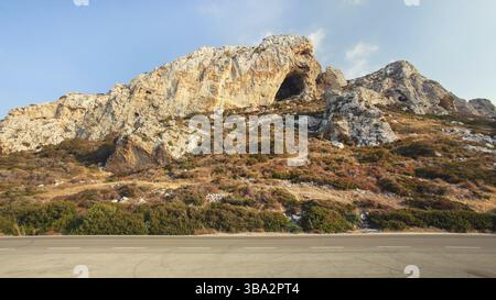 Il sole della sera splende sul paesaggio tipico della regione di Karpass, nella parte settentrionale di Cipro, piccole formazioni rocciose su strada asfaltata, Dipkarpaz, Cipro, Europa Foto Stock