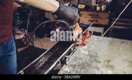 Applicazione di cera calda a base di sci con ferro. Applicazione di cera di sci di fondo sci. Base di sci tuning. Sci wax ferro e barre di cera. Il servizio sci e riparazione. repairman in Foto Stock