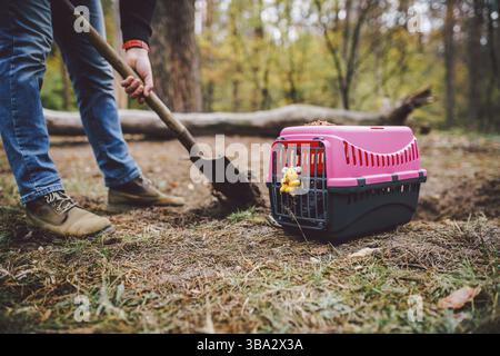 Scena Spooky al cimitero degli animali domestici. La tomba di amici animali perduti. Compagnia, addio. Un uomo porta un animale domestico morto in un vettore alla foresta e di Foto Stock