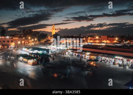 Vista panoramica di piazza Djemaa el Fna, illuminata al tramonto con venditori ambulanti e bancarelle di cibo Foto Stock