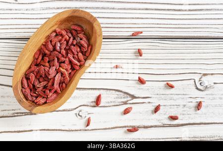 goji essiccato alias. Semi di wolfberry in una ciotola di legno e versati su una scrivania di lavagne bianche vicino a Liptovsky Mikulas, Slovacchia, Europa Foto Stock