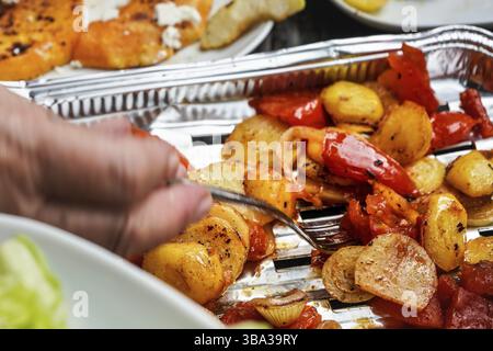 Patate e pomodori grigliati serviti su un vassoio in alluminio direttamente dalla griglia, dettaglio primo piano, Pribylina, Slovacchia, Europa Foto Stock