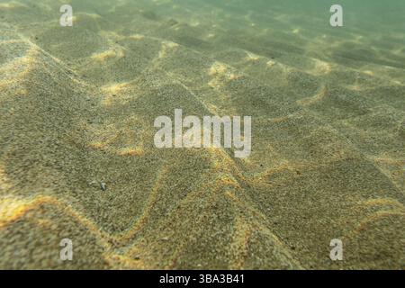 Foto subacquee, fondo marino in acque poco profonde, sole che splende, luce che si rifratta sulle dune di sabbia. Sfondo marino astratto, Lapta, Cipro, Europa Foto Stock