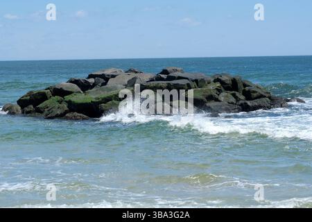 Rompere le onde contro le rocce. Foto Stock