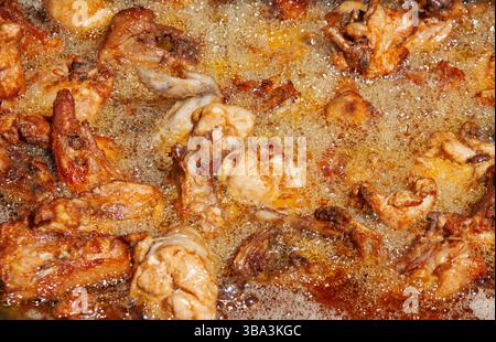 pollo fritto bollente in olio, ali, cosce di pollo, bolle d'olio, alta temperatura, fast food Foto Stock