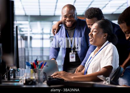 Team di ingegneri felici che ridono e si divertono a vicenda mentre lavorano in un ambiente di lavoro di server farm. I colleghi si divertono insieme durante le pause lavorative negli uffici dei data center Foto Stock