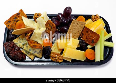 selezione di formaggi assortiti con frutta chutney, noci e cracker in un tagliere di legno Foto Stock