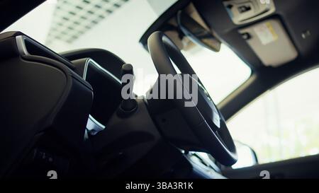 Immagine ravvicinata della leva del cambio, della ruota, del portabicchieri e del quadro di comando della trasmissione della console interna della vettura. Panoramica dei pulsanti di comando del quadro elettronico del cambio marcia del veicolo Foto Stock