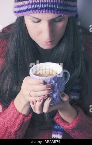 La donna tiene una tazza di tè a maglia con limone Foto Stock