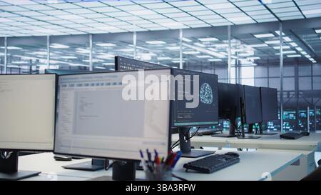 Codice in esecuzione sugli schermi dei computer in uno spazio di lavoro vuoto del data center, utilizzato per la risoluzione dei problemi relativi ai montaggi su rack. Primo piano dello script che lavora sui monitor dei PC desktop che aggiornano i sistemi mainframe nella sala server Foto Stock