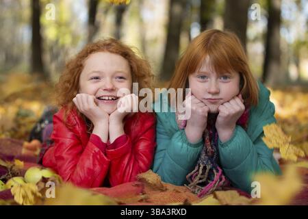 Ritratto di due belle sorelle giace sulle foglie nel parco autunnale Foto Stock