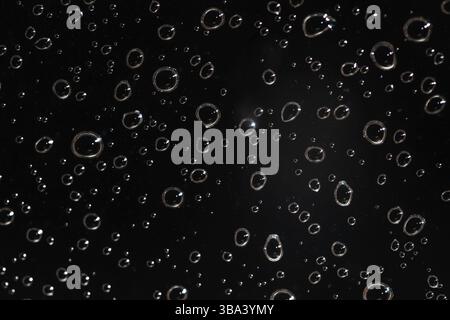 Foto di dettaglio - le gocce d'acqua piovana dietro il vetro sembrano bolle nel liquido nero. Abstract wet background, Liptovsky Hradok, Slovacchia, Europa Foto Stock