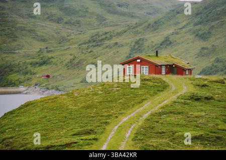 Legno norvegese casa estiva (Hytte) Affacciato sul pittoresco lago, Norvegia, in Scandinavia. Bungalow sul Lago di Garda in zone rurali. Dal tetto di torba hut sul lago. Erba tipica r Foto Stock
