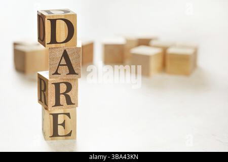 Quattro cubi di legno disposti in pila con il testo DARE (ovvero definire, valutare, rispondere, valutare) su di essi, spazio per testo/immagine nell'angolo in basso a destra, L Foto Stock