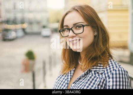 Donna felice e alla moda nella vecchia strada della città europea, momento di spensieratezza e vera felicità. Giovane bella donna allegra che cammina sulla vecchia strada. Europeo Foto Stock