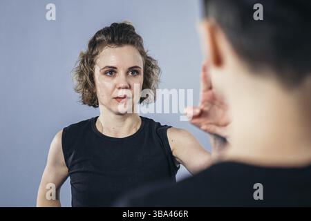 Allenatore insegna all'atleta a colpire il calcio. Forti atleti di arti marziali femminili nella loro formazione taekwon-do. Due giovani donne istruttore e studente che pratica Foto Stock