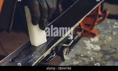 Applicazione di cera calda a base di sci con ferro. Applicazione di cera di sci di fondo sci. Base di sci tuning. Sci wax ferro e barre di cera. Il servizio sci e riparazione. repairman in Foto Stock