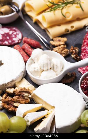 Formaggio e salame con olive e noci su un piatto di ardesia Foto Stock