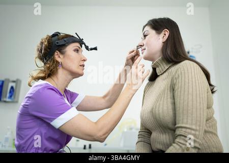 Dottore professionale di otorhinolaringologist che fa esame del naso con otoscopio in ospedale moderno. Congestione nasale, sinusite, allergia concetto Foto Stock