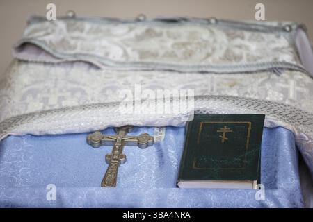 La croce e il libro della Bibbia giacciono sul tavolo della chiesa. La religione Foto Stock