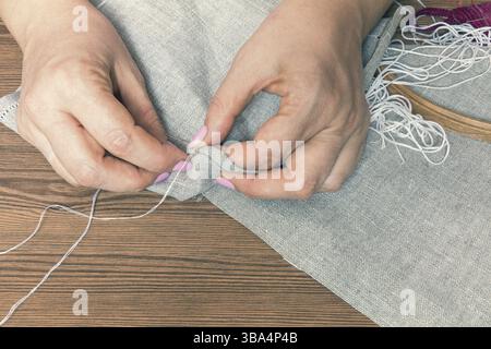 Donna mani facendo openwork ricamo su homespun biancheria. Close up. La colorazione e l'elaborazione di foto Foto Stock