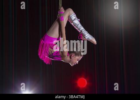 Artista circense acrobat prestazioni. La ragazza esegue elementi acrobatici nell'aria. Circus ginnasta sul palco Foto Stock