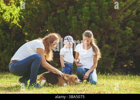 Felice madre con sua figlia, piccolo figlio e cane beagle per una passeggiata Foto Stock