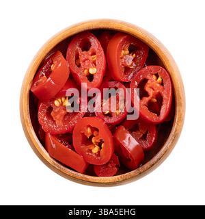Fette di jalapeno rosso sottaceto in un recipiente di legno. Peperoncini rossi piccanti di medie dimensioni, tagliati a sezioni incrociate, pastorizzati e conservati in salamoia. Foto Stock