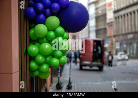 Palloncini verdi e viola vibranti sono disposti all'ingresso di un edificio in una zona vivace. Foto Stock