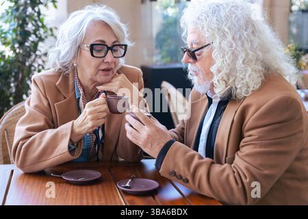 Coppia caucasica senior che parla da vicino mentre beve un caffè al caffè all'aperto Foto Stock