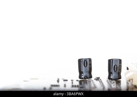 Una vista dettagliata dei condensatori posizionati su una scheda a circuito stampato, evidenziata da uno sfondo bianco, che mostra componenti elettronici e tecnol Foto Stock