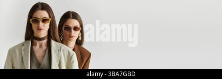 Due eleganti gemelle sfoggiano eleganza attraverso le loro scelte di moda e gli accessori. Foto Stock