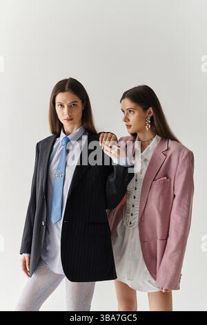 Due eleganti gemelle sfoggiano il loro look unico in abiti alla moda. Foto Stock