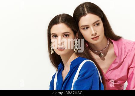Due splendide gemelle mostrano il loro stile unico mentre si uniscono in un elegante ambiente interno. Foto Stock