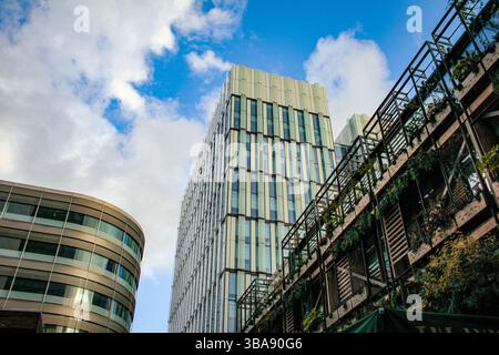 Deansgate, Manchester, Regno Unito - 11.16.2024: Alte strutture sfalsate con vaste vetrate, che brillano al sole. Foto Stock