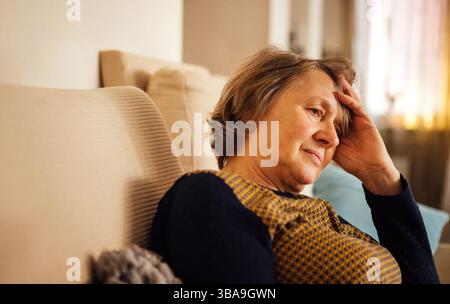 Primo piano di una donna anziana che soffre di mal di testa. La signora matura ha chiuso gli occhi Foto Stock