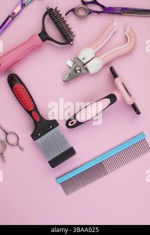 Strumento per il groomer su sfondo rosa. Accessori per la cura del cane. Pettini e spazzole per animali. Vista dall'alto Foto Stock