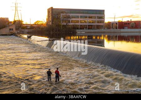Grand Rapids, Michigan, USA - 04-23-2025: Foto di persone che pescano e si rilassano vicino al fiume a Grand Rapids Michigan al tramonto con viste panoramiche e cal Foto Stock