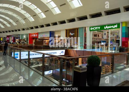 Un moderno centro commerciale interno con numerosi negozi, ringhiere di vetro e illuminazione luminosa. Il centro commerciale ha una disposizione spaziosa con negozi vi Foto Stock