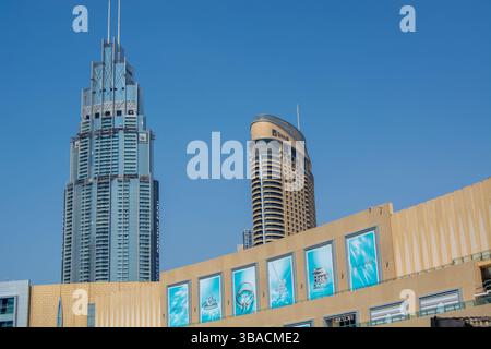 Vista di due moderni grattacieli su un cielo azzurro. L'edificio di sinistra presenta un design affilato e angolare con una guglia, mentre l'edificio di destra h Foto Stock