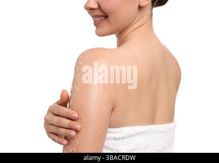 Donna sorridente che applica uno scrub per il corpo sul braccio su sfondo bianco Foto Stock