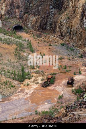 Nell'ex miniera di rame di Falun, Svezia, i veicoli bulldozer arrugginiti e il cratere mostrano il passato industriale del sito e la bonifica della natura. Foto Stock