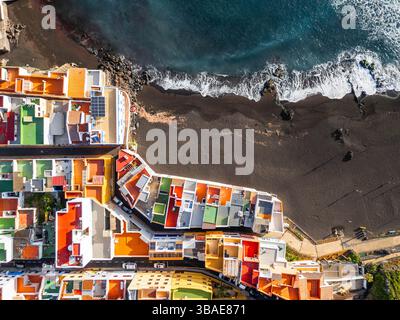 Vista aerea dall'alto su case colorate e spiaggia nera nel piccolo villaggio di pescatori, Punta Brava, Tenerife, isole Canarie, Spagna Foto Stock
